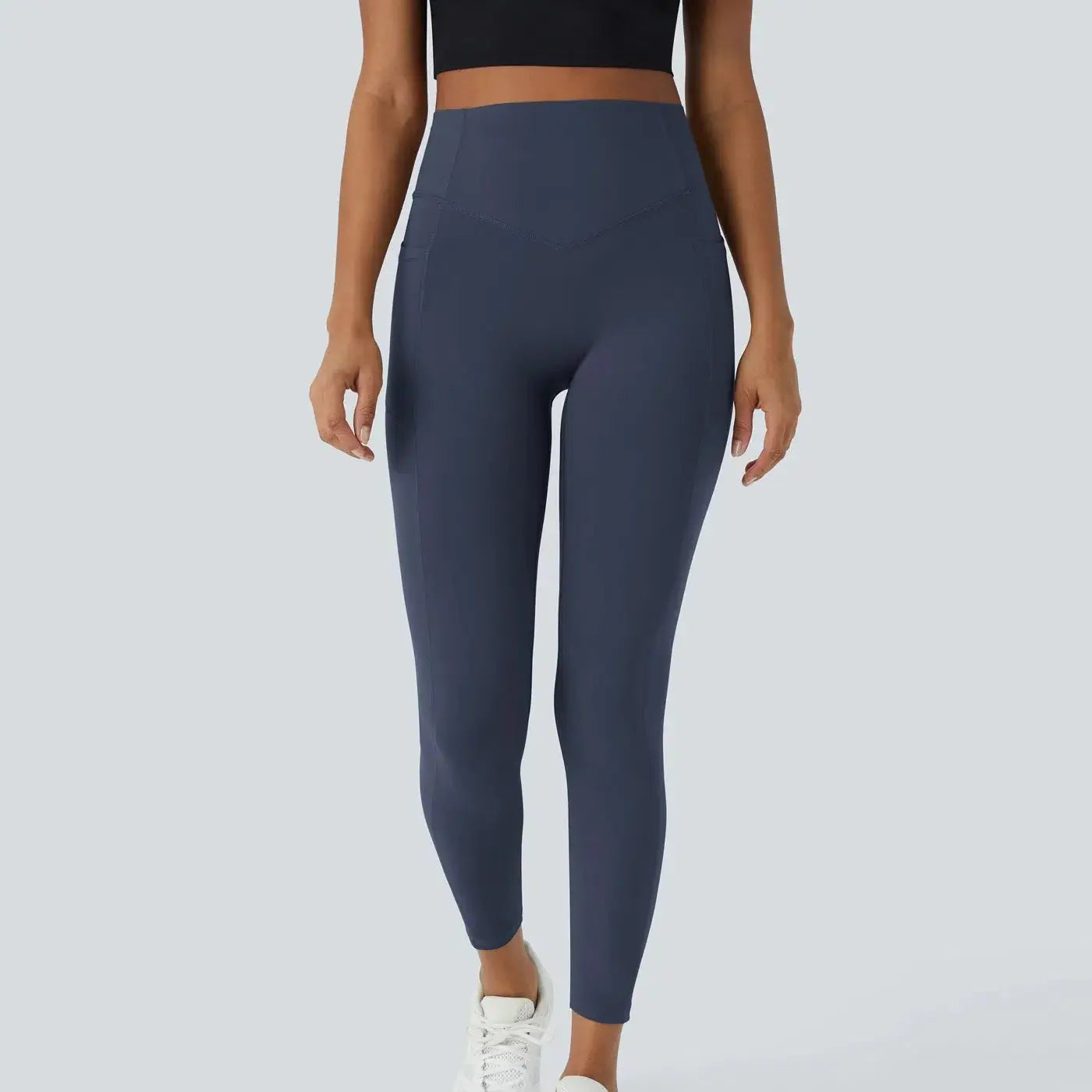 Person wearing dark blue leggings on a light gray background